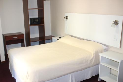 a bedroom with a white bed and a nightstand at Hotel Catedral San Rafael in San Rafael