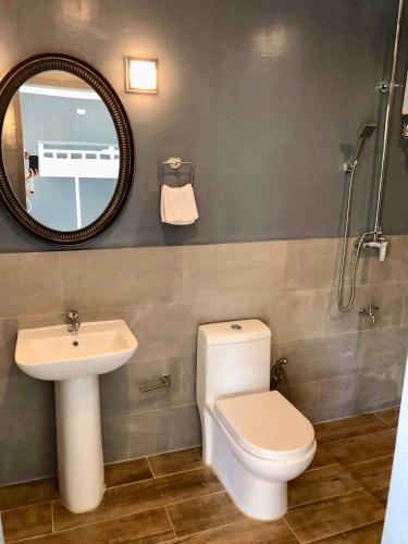 a bathroom with a toilet and a sink and a mirror at PAYAG SUITES in General Luna