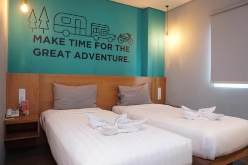two beds in a room with a sign that says make time for the great adventure at Radja Art and Boutique Hotel Simpang Lima in Semarang