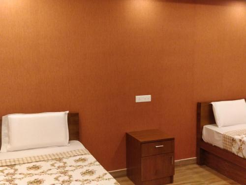 a bedroom with two beds and a nightstand at Majestic Inn in Trivandrum