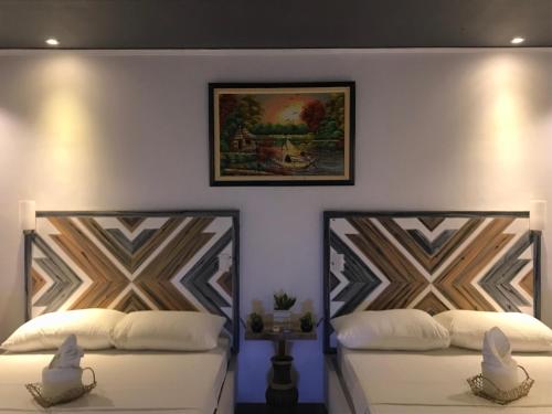two beds in a room with a picture on the wall at PAYAG SUITES in General Luna