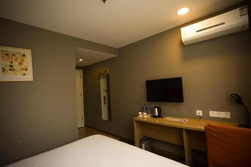 a room with a bed and a desk with a television at Home Inn Xi'an South Taihua Road Daming Palace Relics Park in Xi'an