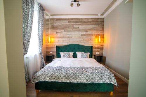 a bedroom with a green bed and a brick wall at Garrison's Suites in Câmpulung Moldovenesc