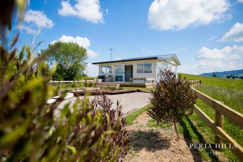 a small house in a field with a fence at Peria Hills Cottage in Matamata