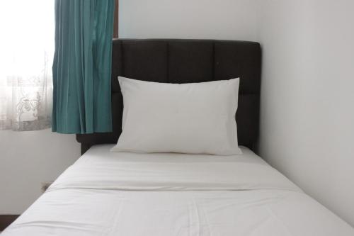 un letto con testiera nera e cuscino bianco di Homey 2BR Majesty Apartment near Maranatha University By Travelio a Bandung