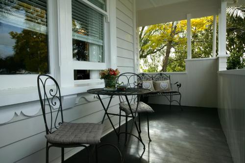 porche con 2 sillas, mesa y 2 ventanas en Eden Park Bed And Breakfast Inn, en Auckland