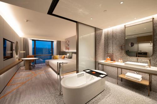 Crowne Plaza Beijing Badaling, an IHG Hotel في Yanqing: حمام مع حوض ومغسلة وسرير