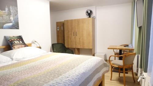a bedroom with a bed and a desk and a cabinet at Hotel Garni Villa Areka in Český Krumlov