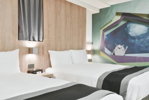 a hotel room with two beds and a painting at Trans Inn in Taichung