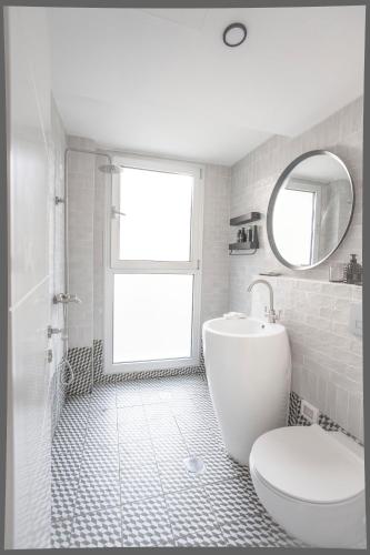 a white bathroom with a toilet and a mirror at Etis garden seafront in Haifa