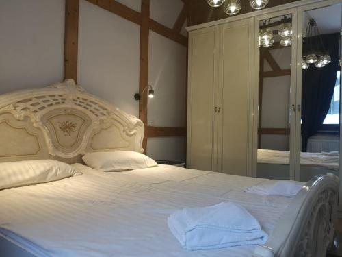 - une chambre avec un grand lit blanc et un miroir dans l'établissement Hotel & Hostel Drei Bären, à Altenau