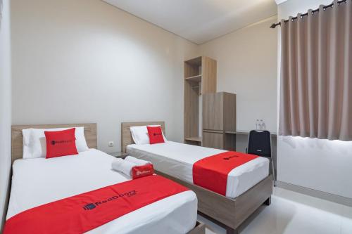 a room with two beds with red and white sheets at RedDoorz Plus @ Cirebon City Center in Cirebon