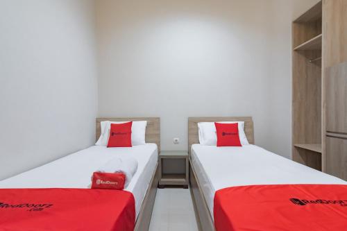 two beds with red pillows in a room at RedDoorz Plus @ Cirebon City Center in Cirebon