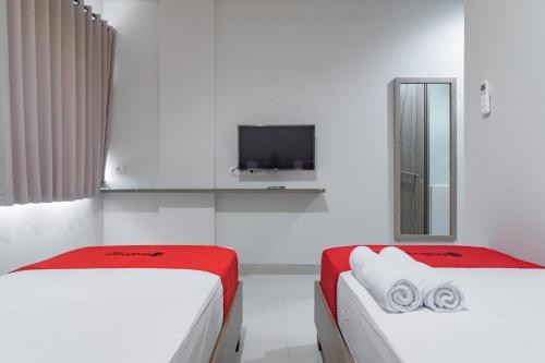 a white room with two beds and a tv at RedDoorz Plus @ Cirebon City Center in Cirebon