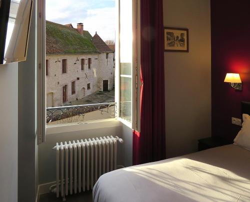 1 dormitorio con ventana, cama y radiador en Hôtel Le Dormeux, en Mehun-sur-Yèvre