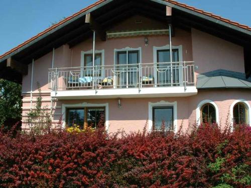 a pink house with a balcony and some bushes at Haus Obermayer in Laufen