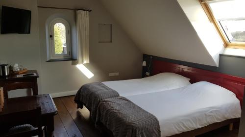 a small bedroom with two beds and a window at Hart van Bourdonck in Boerdonk