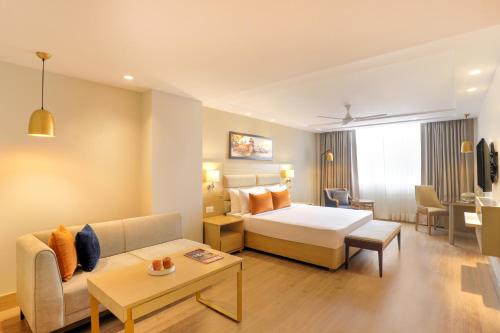 アリーガルにあるLemon Tree Hotel, Aligarhのベッドとソファ付きのホテルルーム