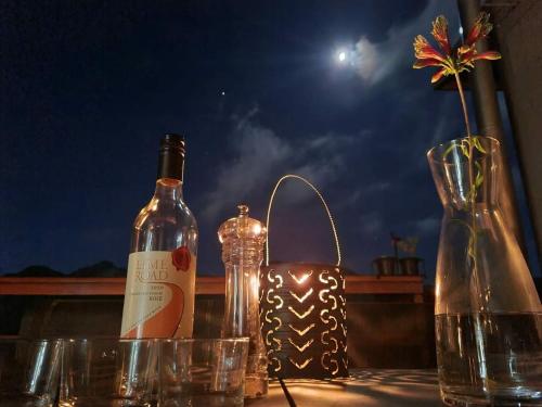 a bottle of wine and glasses on a table at Cabin in da Woods in Cape Town