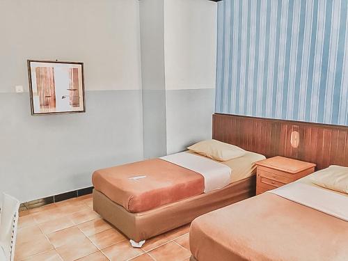 a small room with two beds and a mirror at Hotel Aida Syariah Mitra RedDoorz in Samarinda