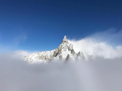 a mountain covered in snow and clouds in the sky at Hotel Coeur Du Village in La Thuile