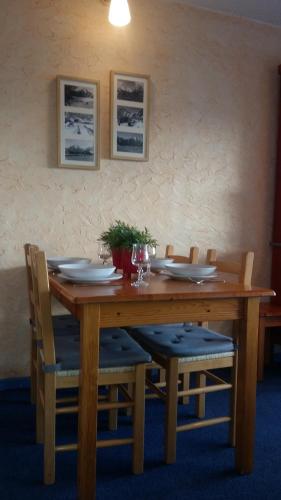 einen hölzernen Esstisch mit Stühlen und Tellern in der Unterkunft Le Tyrol in Les Deux Alpes