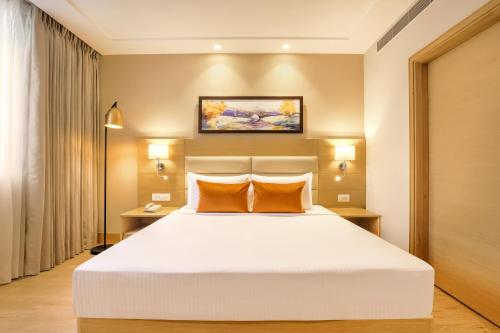 a bedroom with a large white bed with two orange pillows at Lemon Tree Hotel, Aligarh in Alīgarh