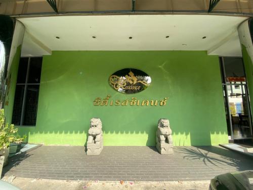 a green building with two statues in front of it at City Residence in Bangkok