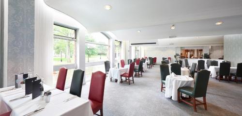 St James Hotel في غريمسبي: غرفة طعام مع طاولات بيضاء وكراسي حمراء