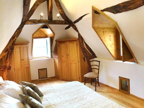a bedroom with a bed and a window and wooden ceilings at Maison O'Galop in Beynac-et-Cazenac