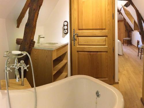 a bath tub in a bathroom with a wooden door at Maison O'Galop in Beynac-et-Cazenac