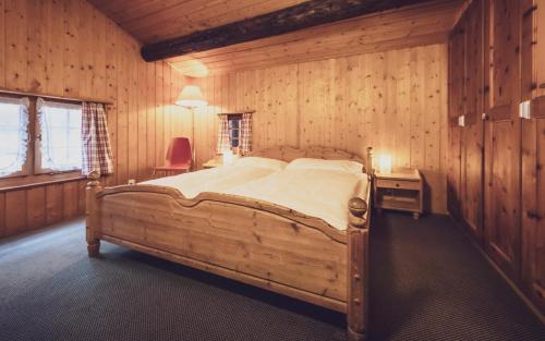 ダボスにあるDavoser Hüsli by Mountain Hotelsの木製の部屋に大型ベッドが備わるベッドルーム1室が備わります。