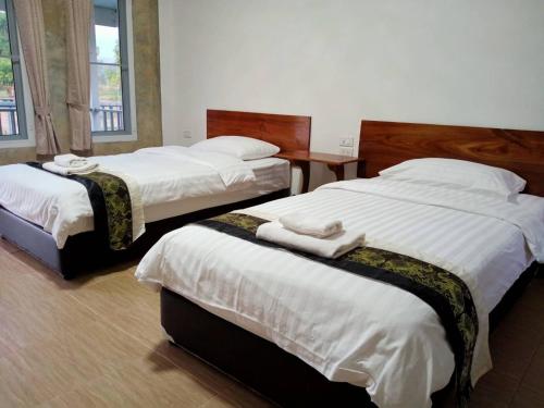 two beds in a hotel room with white sheets at Jeerang Countryside Resort in Mae Hong Son