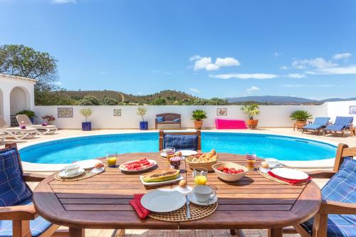 a wooden table with food on it next to a pool at Villa Sagres in Portimão