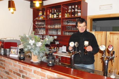 a man standing at a bar holding a glass at Penzion Slunečno in Dobšín