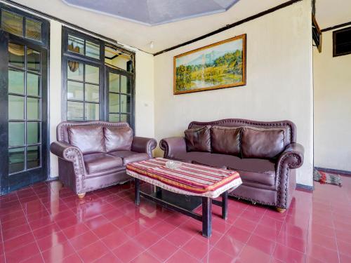 a living room with two leather couches and a coffee table at Hotel Mataram Cipanas Syariah Mitra RedDoorz in Pasakon 1