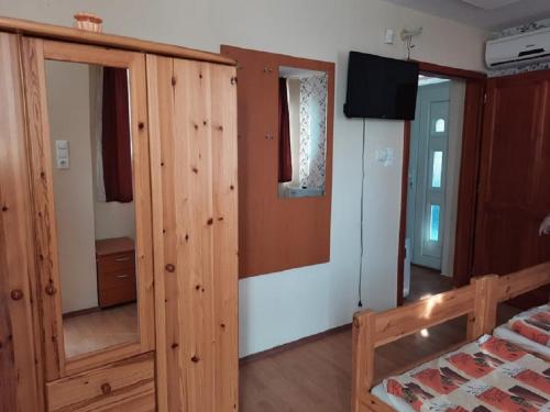 a bedroom with a wooden closet and a bed and a television at Horgász-Lak vendégház in Nagybaracska