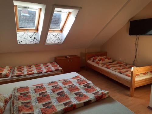 a attic room with two beds and a flat screen tv at Horgász-Lak vendégház in Nagybaracska