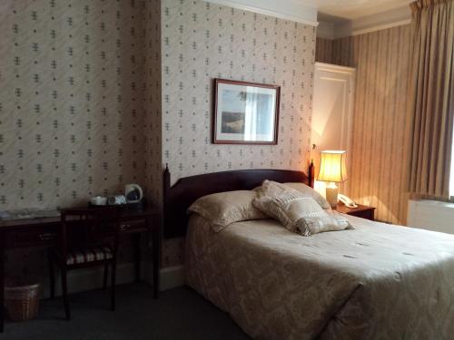 a bedroom with a bed and a table with a lamp at Beech House Hotel in Reading