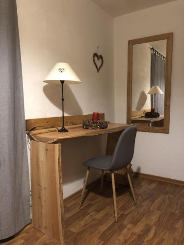 a desk with a lamp and a chair and a mirror at Hotel Coeur Du Village in La Thuile