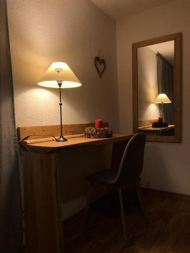 a desk with a lamp and a chair and a mirror at Hotel Coeur Du Village in La Thuile
