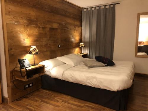 a bedroom with a bed with a wooden wall at Hotel Coeur Du Village in La Thuile