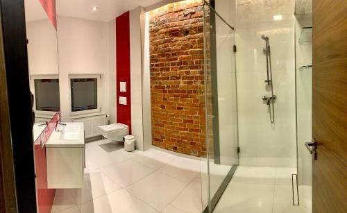 baño con ducha y pared de ladrillo en Apartamenty Młyńska 4, en Gliwice