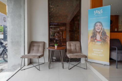 two chairs and a table and a sign in a building at Sans Hotel Ekkon Yogyakarta by Reddoorz in Ngabean