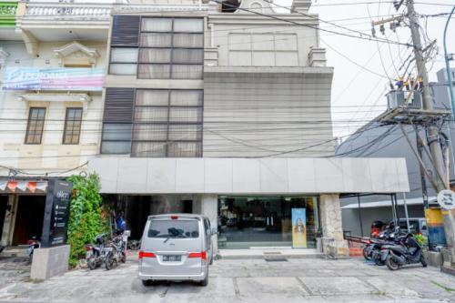 a white car parked in front of a building at Sans Hotel Ekkon Yogyakarta by Reddoorz in Ngabean