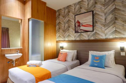 a room with two beds and a sink in it at Sans Hotel Ekkon Yogyakarta by Reddoorz in Ngabean
