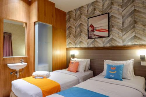 two beds in a hotel room with a sink at Sans Hotel Ekkon Yogyakarta by Reddoorz in Ngabean
