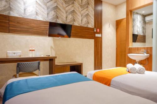 a hotel room with two beds and a sink at Sans Hotel Ekkon Yogyakarta by Reddoorz in Ngabean