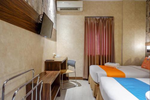 a hotel room with two beds and a television at Sans Hotel Ekkon Yogyakarta by Reddoorz in Ngabean