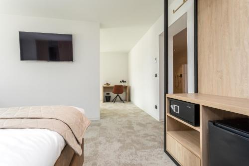 a bedroom with a bed and a flat screen tv at Hotel de Rousch - 4 sterren Superieur in Heerlen